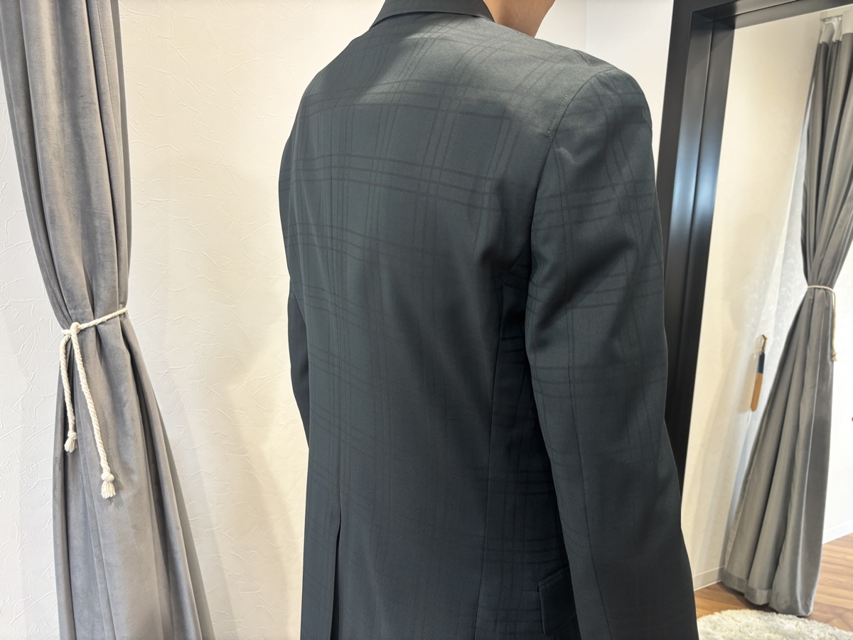 ジャケットの肩から背中にかけてのアップ。光の角度でシャドーチェックの柄が浮かび上がっている