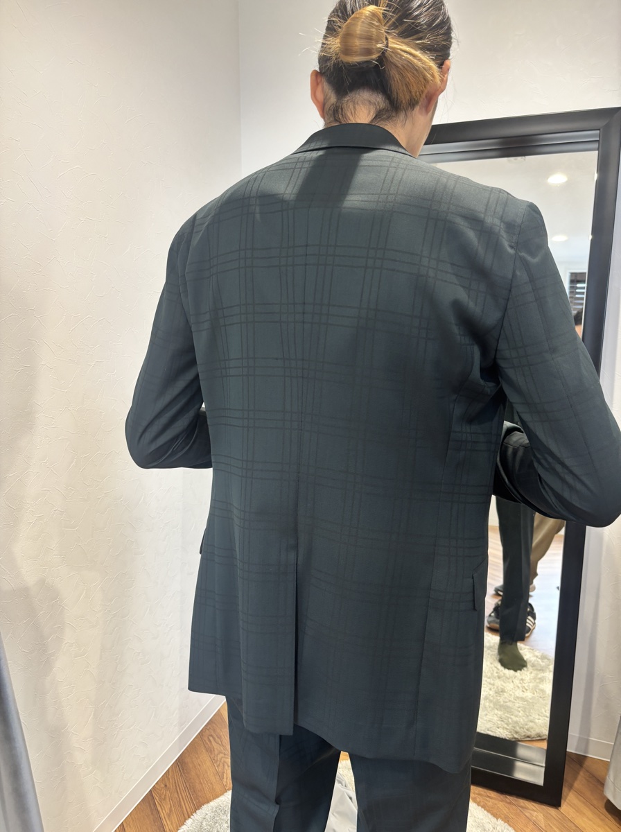 鏡の前に立つ後ろ姿。肩から裾にかけてすっきりと流れるシルエット